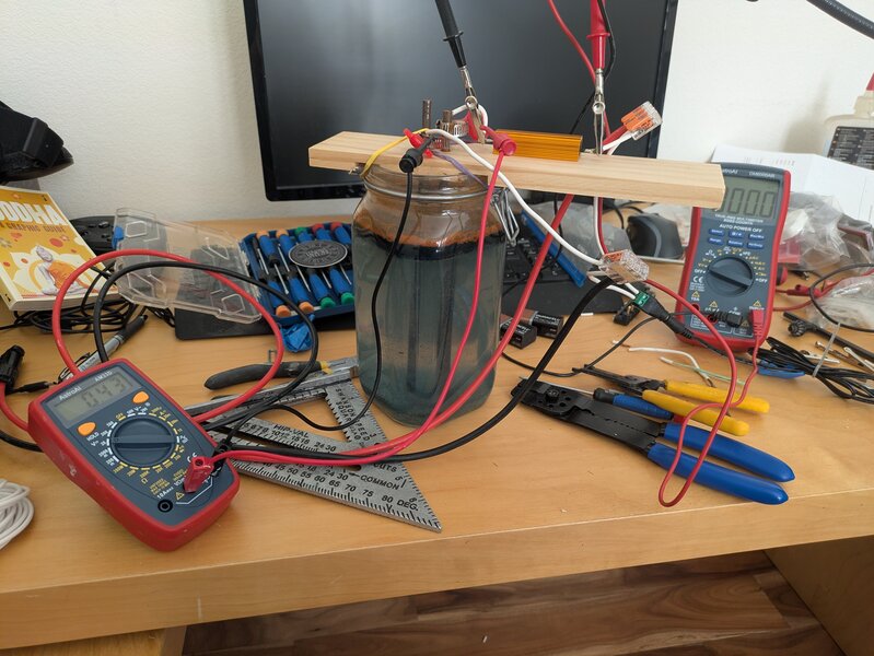 Overview of the rheostat setup, a glass jar filled with salty water, with two steel rods in a wood plate, dipping into the water with an adjustable depth.